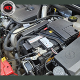 Close-up of a car engine with visible battery and components, featuring the installed tracking device