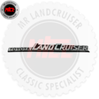 A chrome and black Toyota Land Cruiser emblem badge shown against a white background with a large gray MR Land Cruiser watermark and a small MR Land Cruiser specialist seal in the top-left corner.